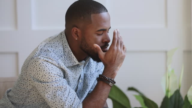 Depressed young black man troubled with debt or guilt regret of mistake thinking of problem, anxious african american guy sit alone at home feeling headache stressed or worried about failure concept